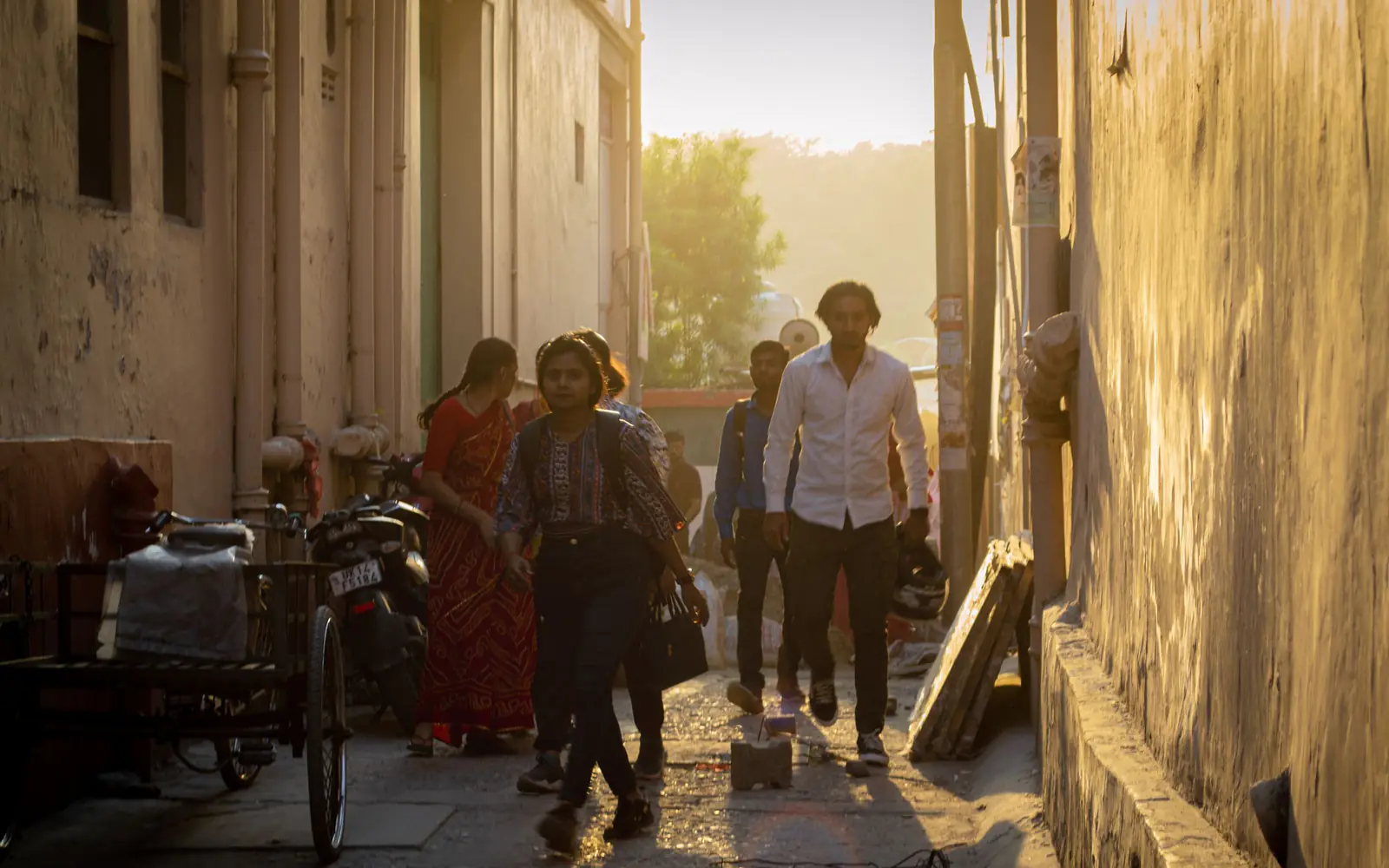People walking through a sunlit street between older buildings
