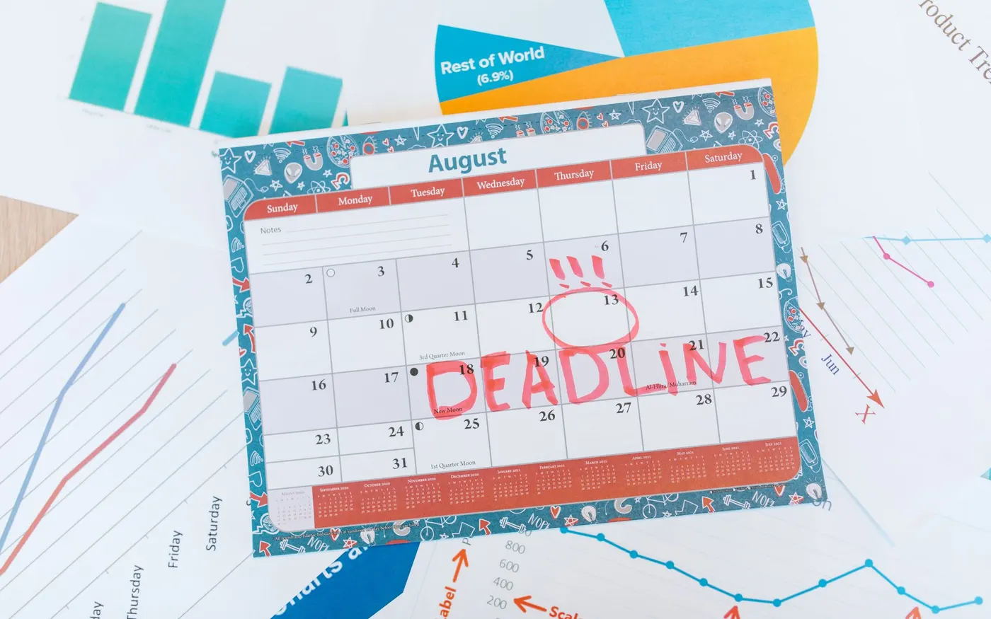 A calendar with a deadline marked in red beside printed charts